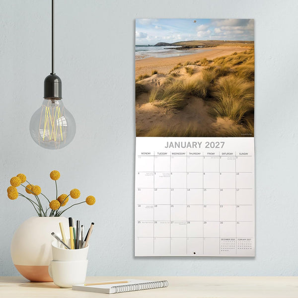 Cornwall Calendar for January 2027 on a wall with decorative items below.