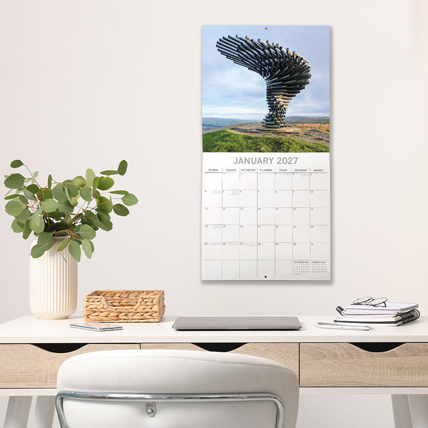 2027 Lancashire Calendar on a wall above a desk with a plant and office supplies.