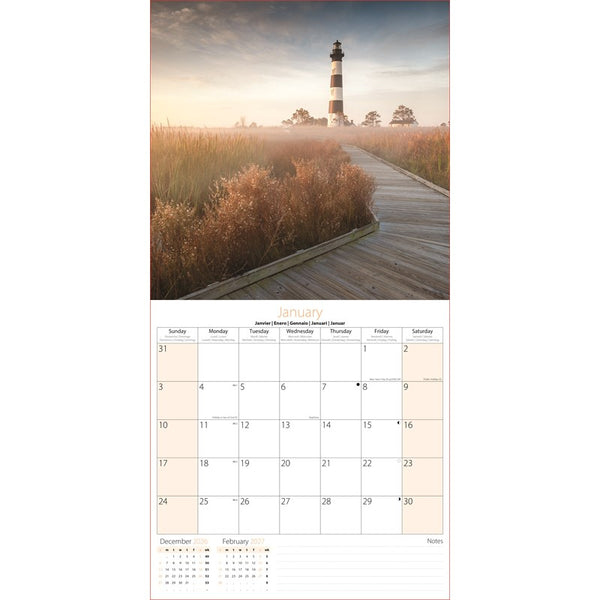 A vertical wall calendar page featuring a scenic photograph of a lighthouse at sunrise above a January calendar grid with days, months, and a notes section.