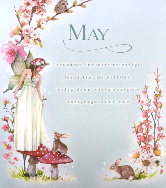 A decorative May-themed illustration with the word MAY at the top, surrounded by a fairy in a white dress, pink blossoms, mushrooms, flowers, and two rabbits on a pale blue background.
