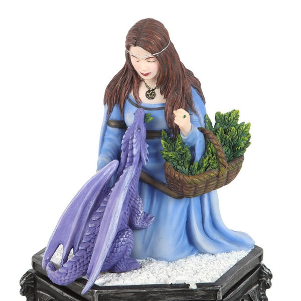 Statue of a woman in a blue dress with a purple dragon and basket of greenery on a white background