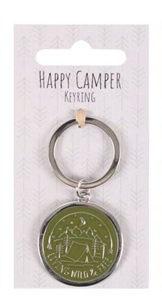 A silver metal keyring with a round green enamel charm featuring a camping scene and the words 'HAPPY CAMPER' and 'MILD WAY', attached to a white card labeled 'HAPPY CAMPER KEYRING'.