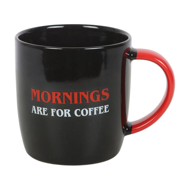 Black mug with red handle and text 'Mornings are for Coffee' on a white background