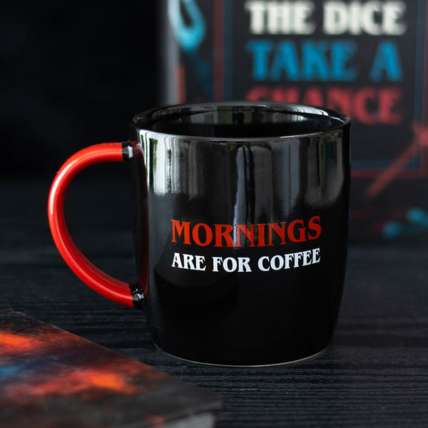 Black mug with red handle and text 'MORNINGS ARE FOR COFFEE' on a dark background