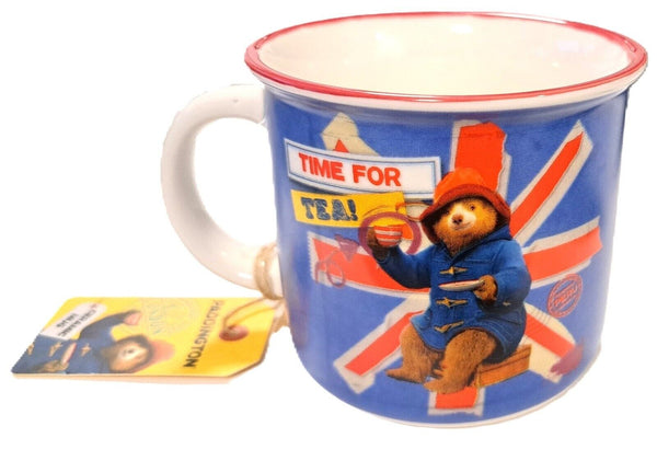 A ceramic mug featuring a colorful illustration of Paddington Bear sitting down holding a cup of tea, with the text 'Time for Tea' and a Union Jack design.